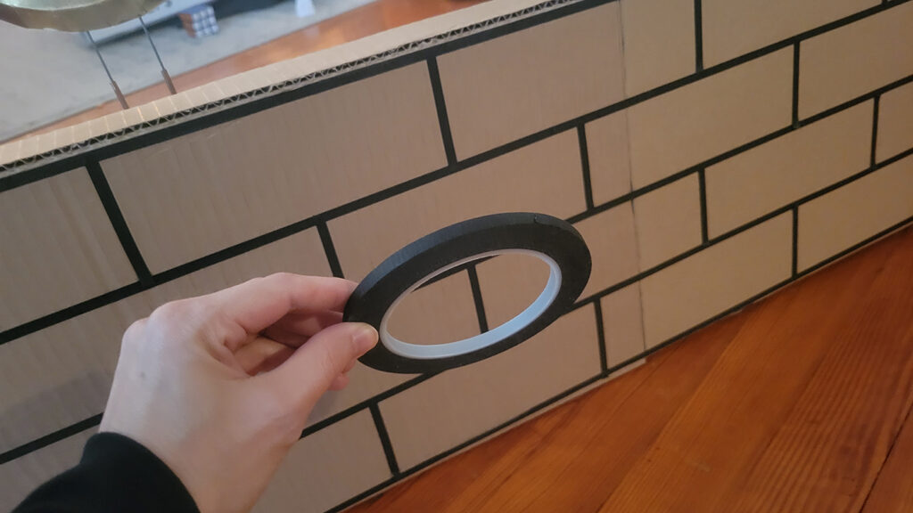 Using thin black tape to create a brick effect on cardboard